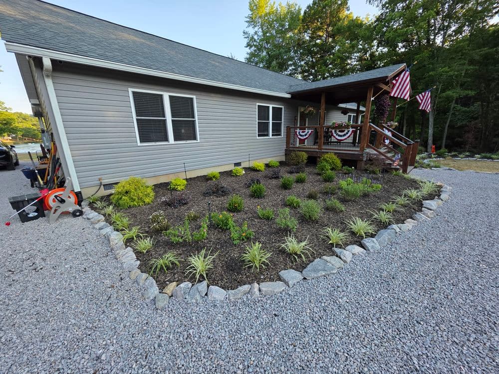 Well-maintained front yard garden with shrubs and decorative stones beside a house.