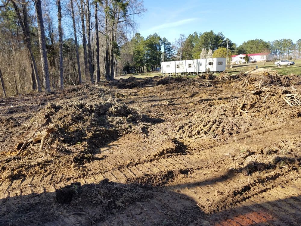 Cleared land with tree debris, showing preparation for construction or landscaping in rural area.