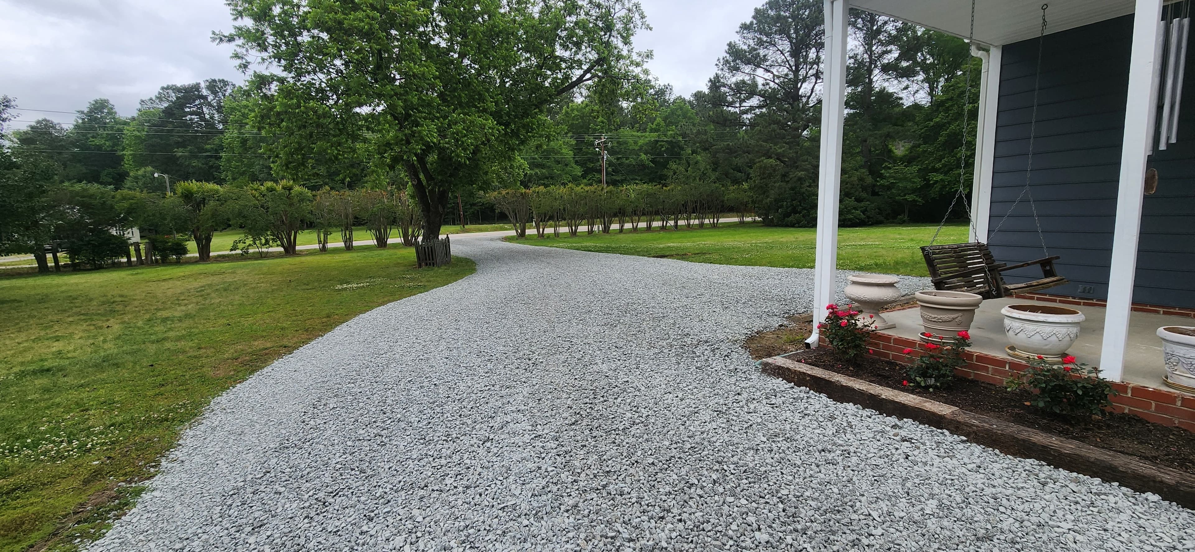 Finished gravel driveway with clean stone surface leading to landscaped property
