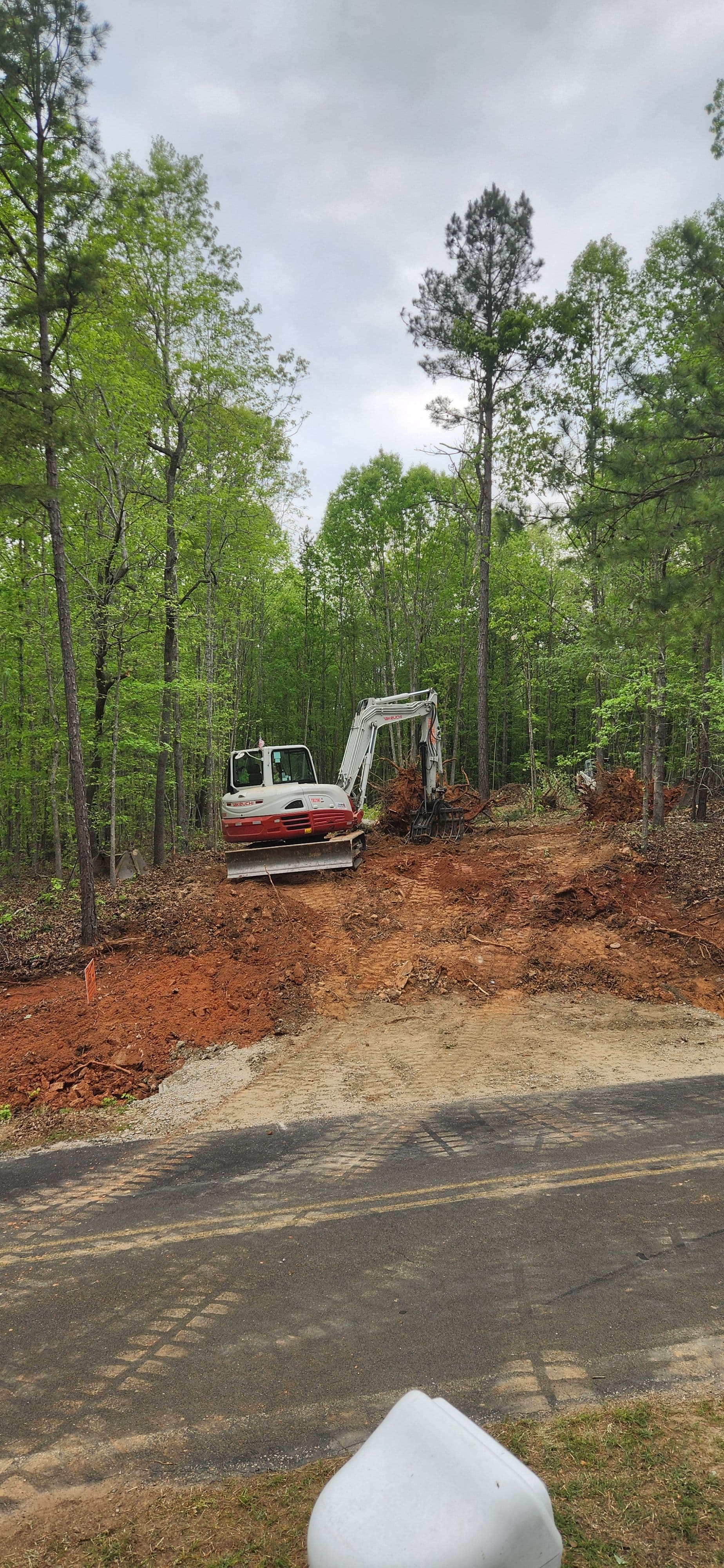 Excavator and bulldozer clearing land in a wooded area for construction.