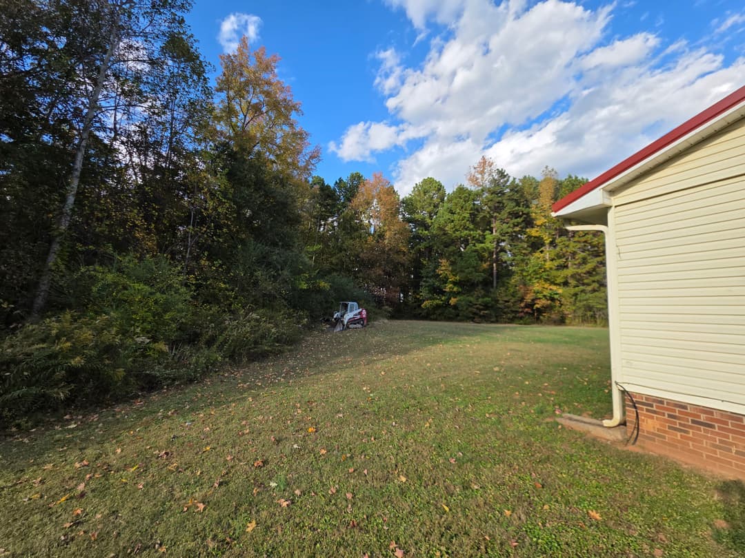 Side view of a house with autumn trees and a parked vehicle in the background.