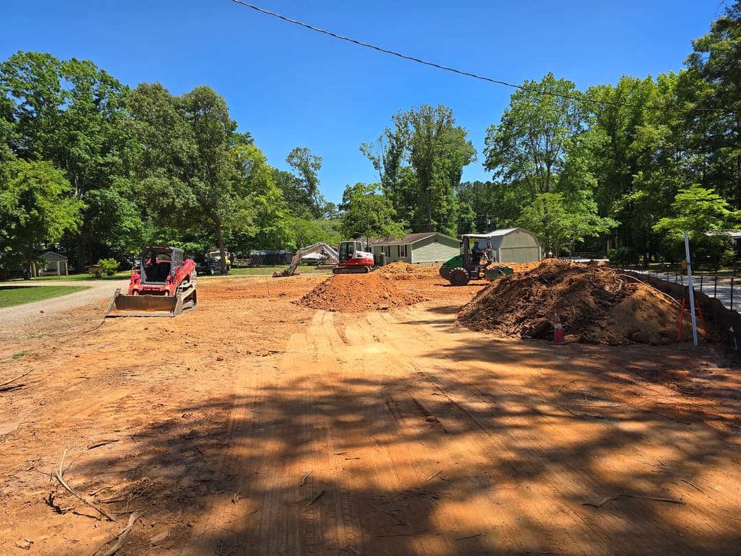 Construction site with heavy machinery and dirt piles under a clear blue sky.